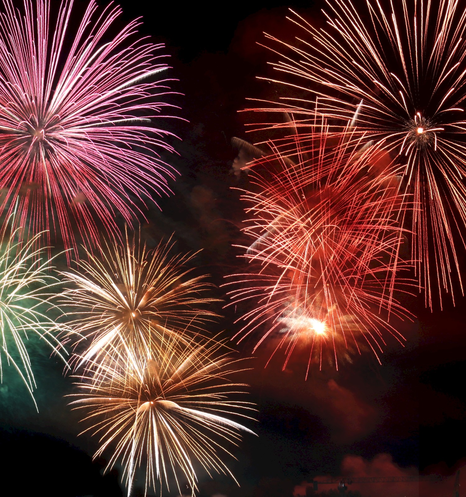 The image shows colorful fireworks bursting against a dark sky, creating a vibrant display with various colors and patterns.