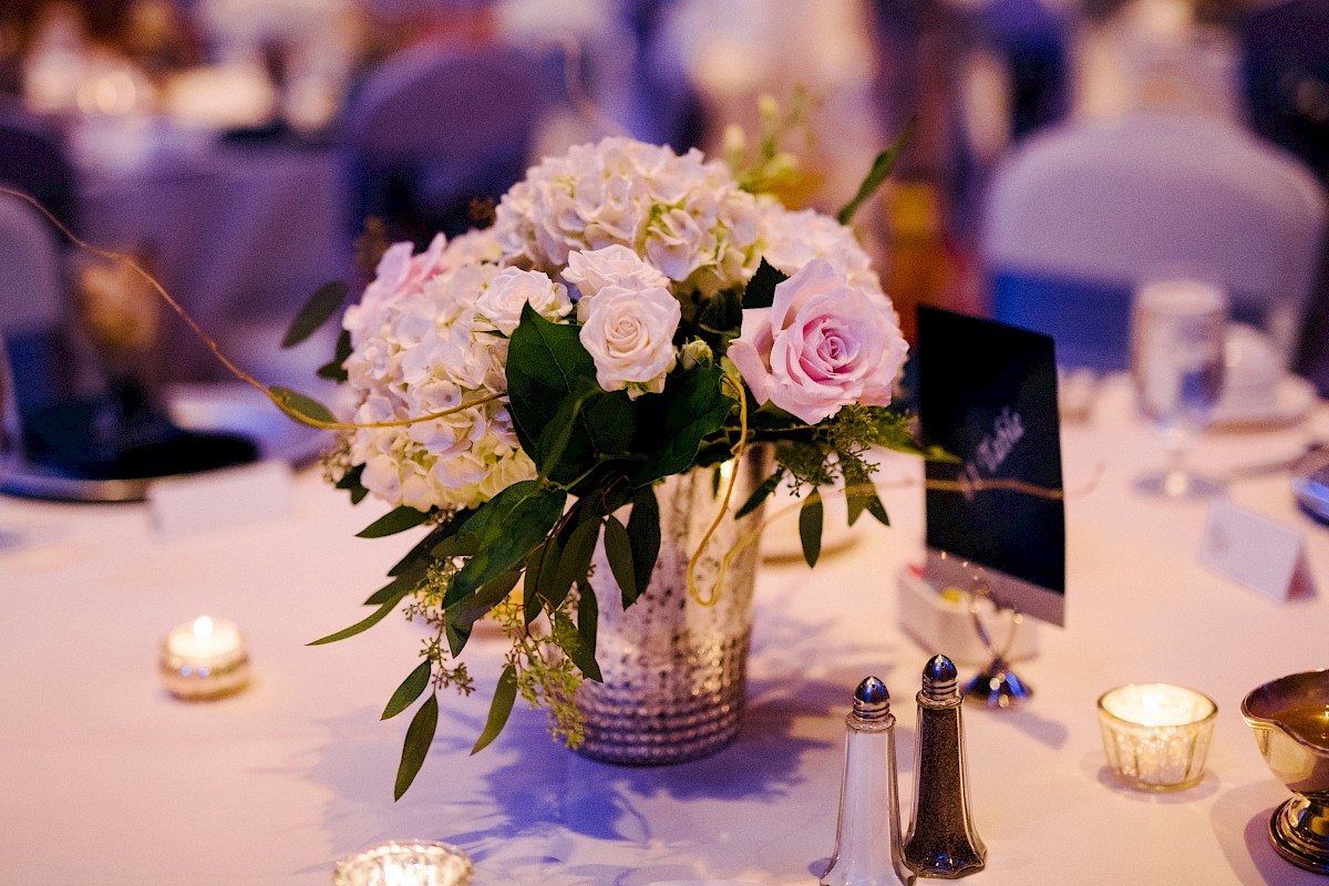 A table is elegantly set with flowers, candles, glassware, and a menu card, creating a warm and inviting atmosphere.